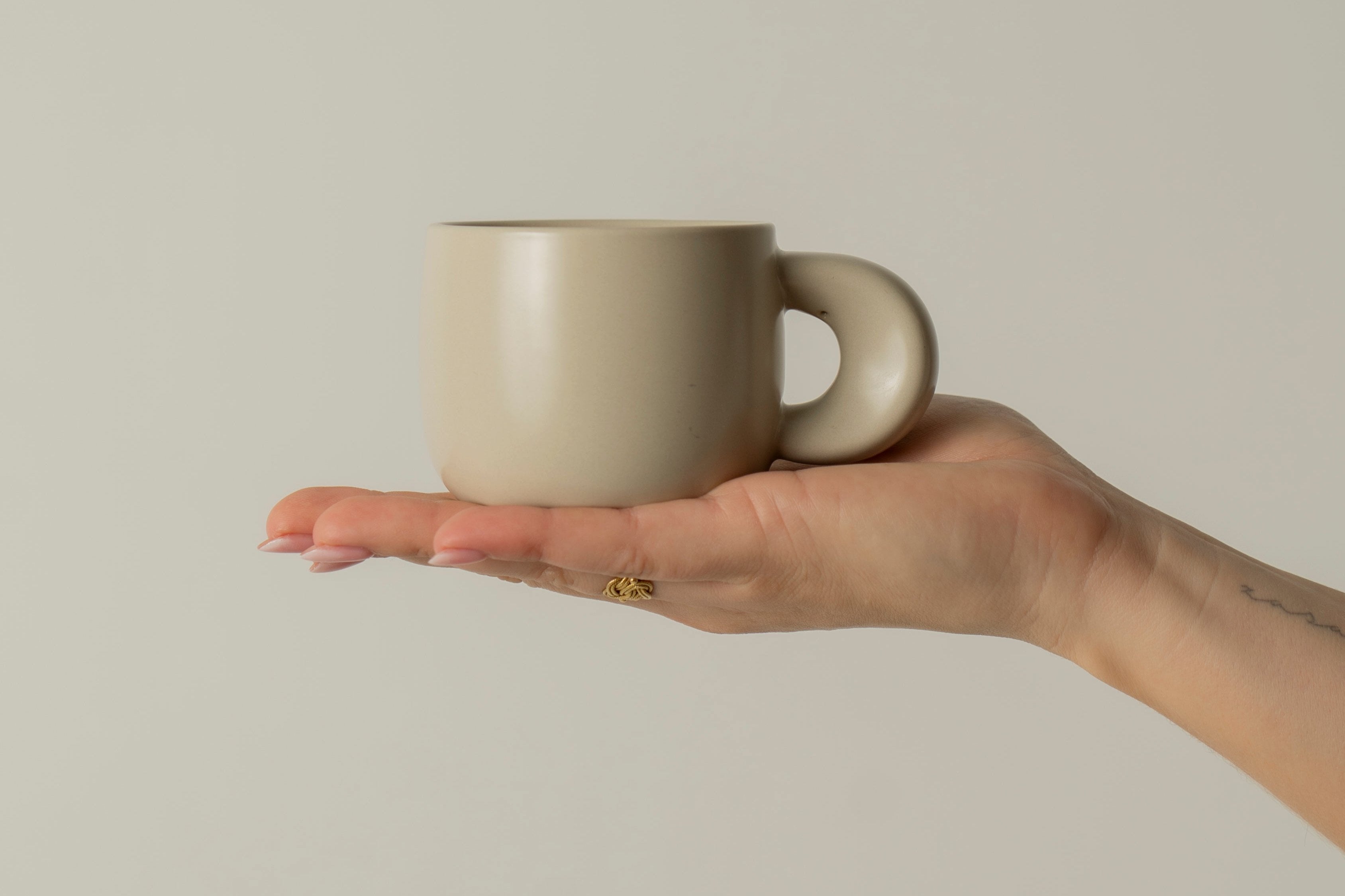 Our ceramic cup Elegance in beige color placed in a hand.