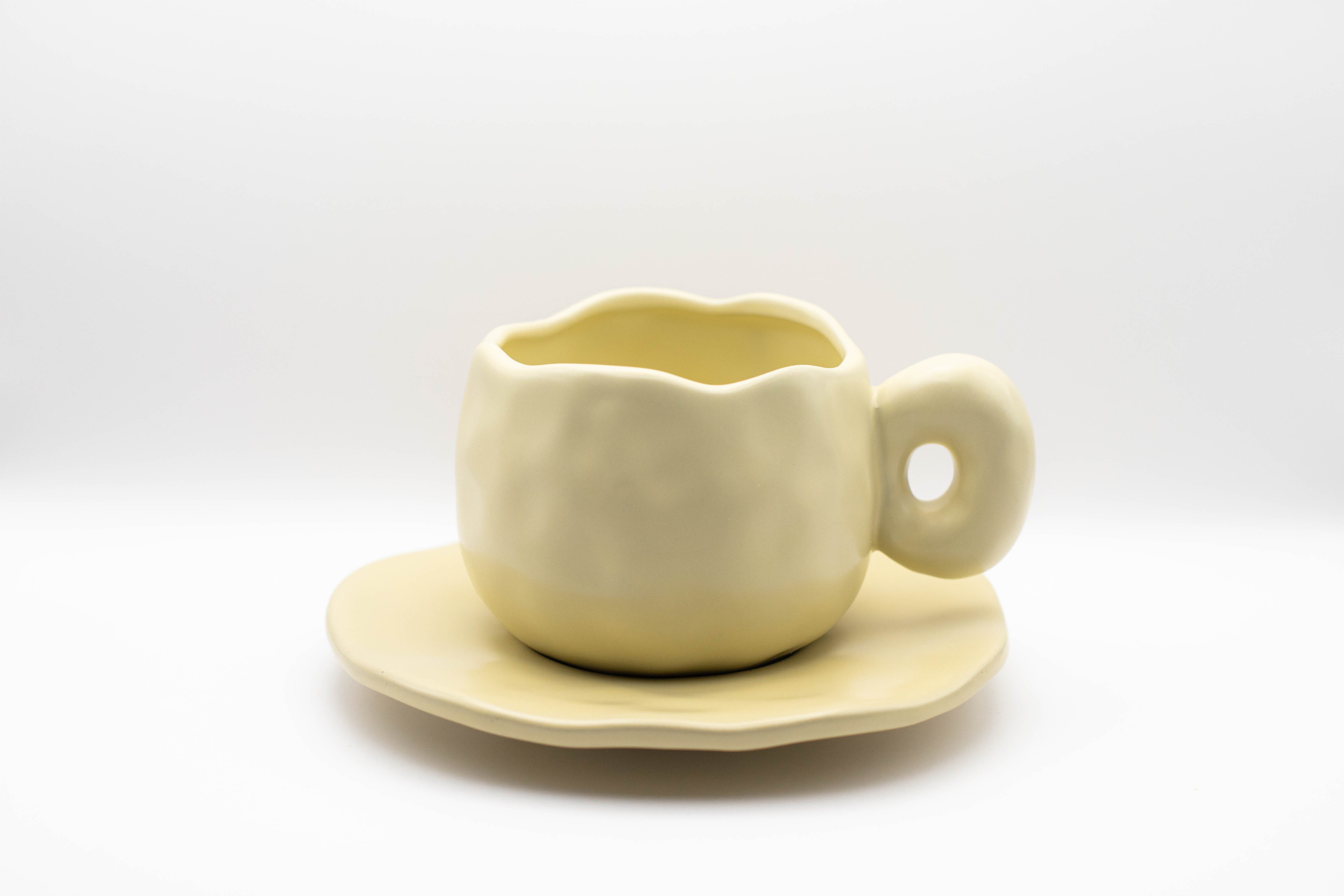 Stand-alone picture of our ceramic Curve cup in a soft beige/yellow pastel color. 