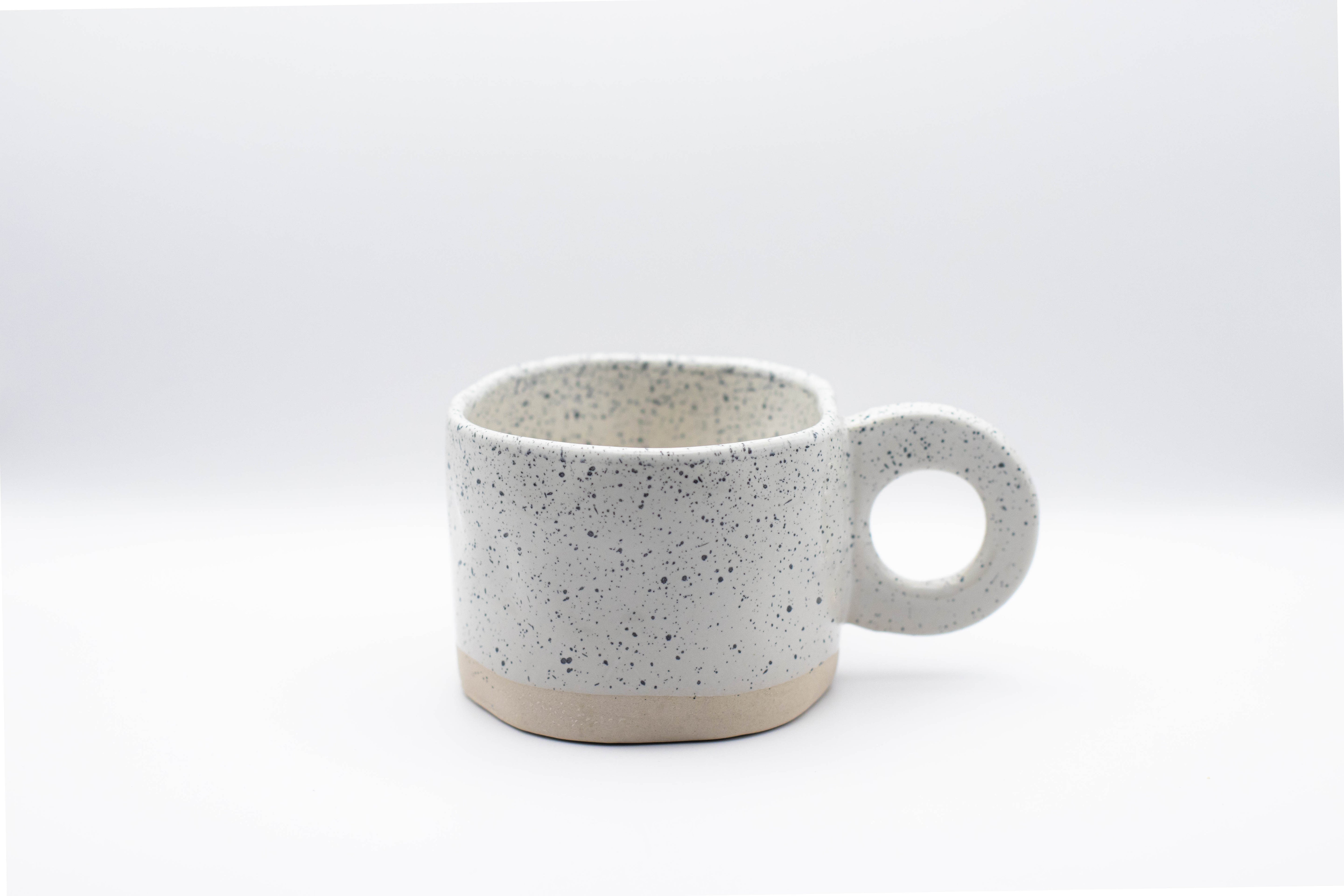 Stand-alone product picture of our white ceramic cup Dotty with black little dots.