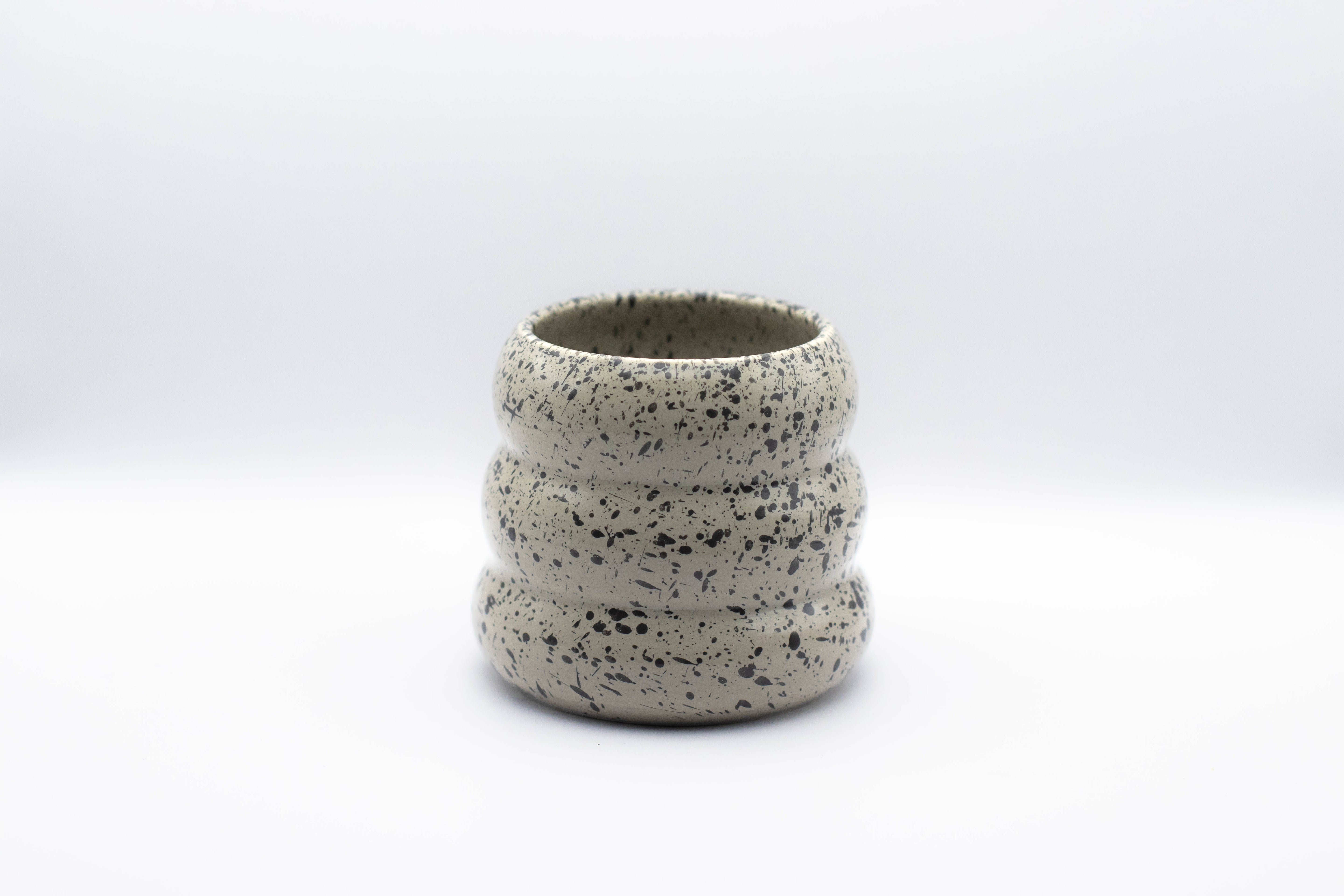 Stand-alone picture of our 3-layered ceramic mug "Sprinkled Donut" in grey with black paint splashes. 