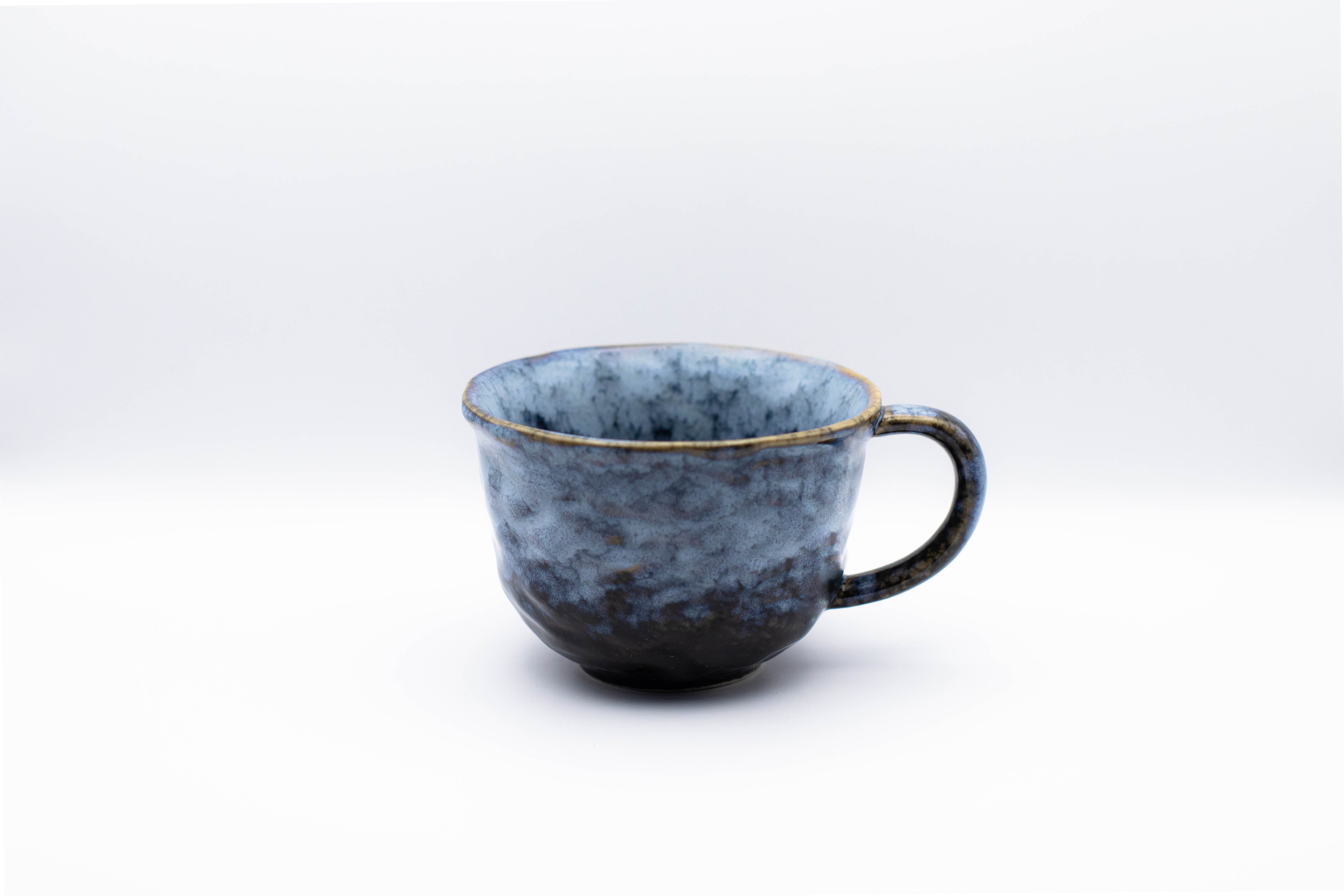 Stand-alone picture of our ceramic Sora cup with wobbly texture in a blue color.