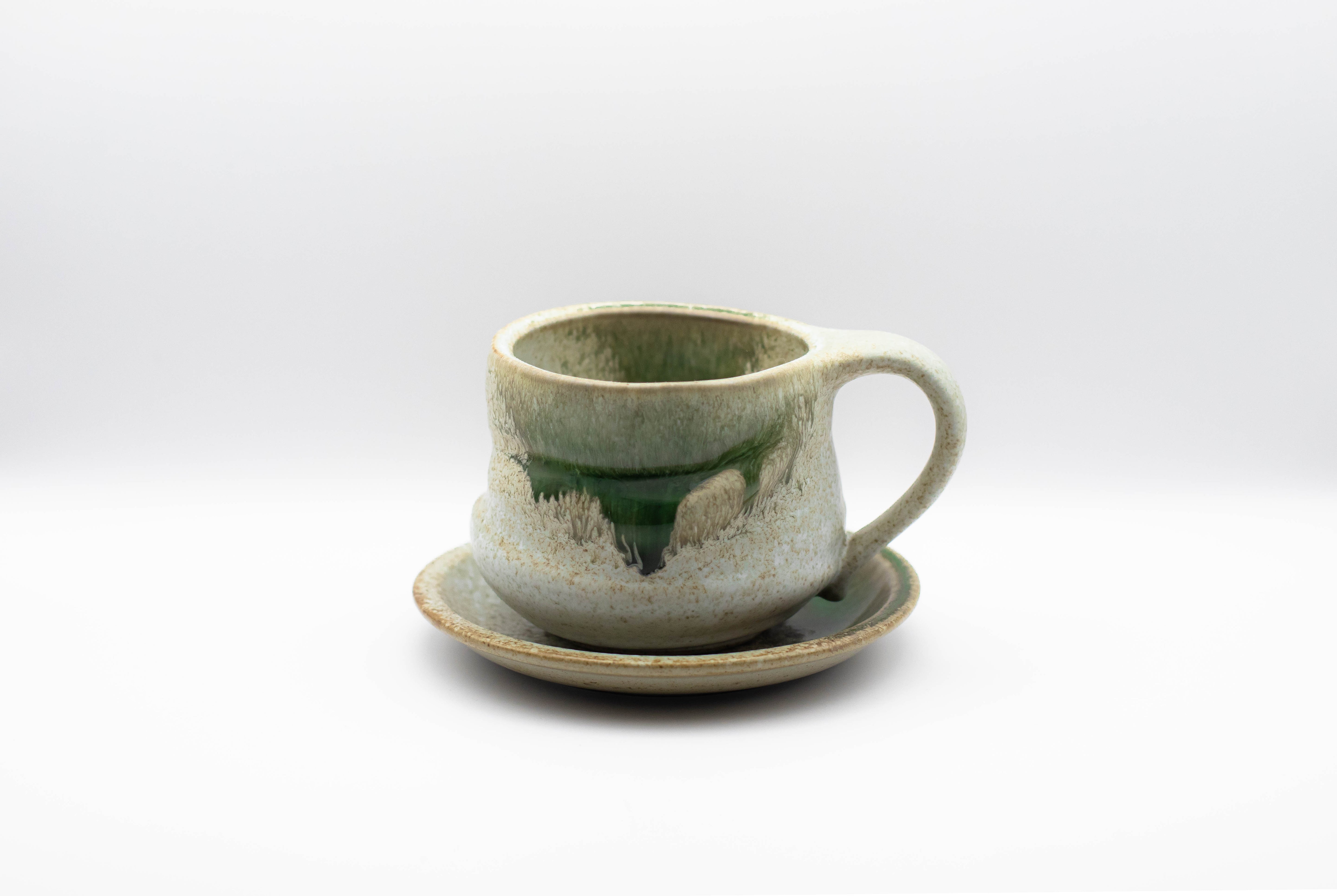 A stand-alone product picture of our ceramic cup Tsuyu in a stone-grey color with bits of emerald green.