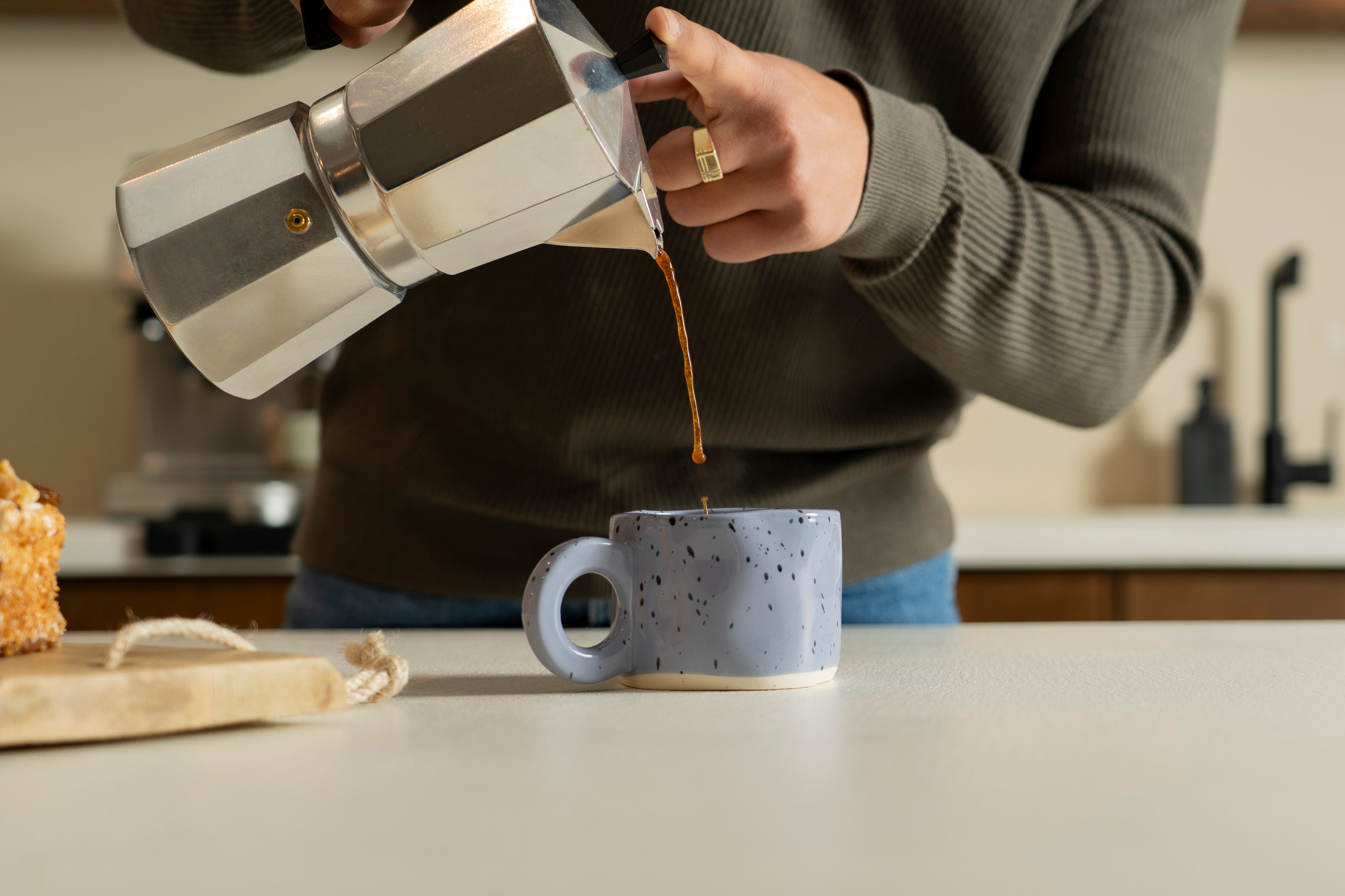 Someone pouring coffee into our ceramic cup "Dotty" in the color purple with black paint splashes. 