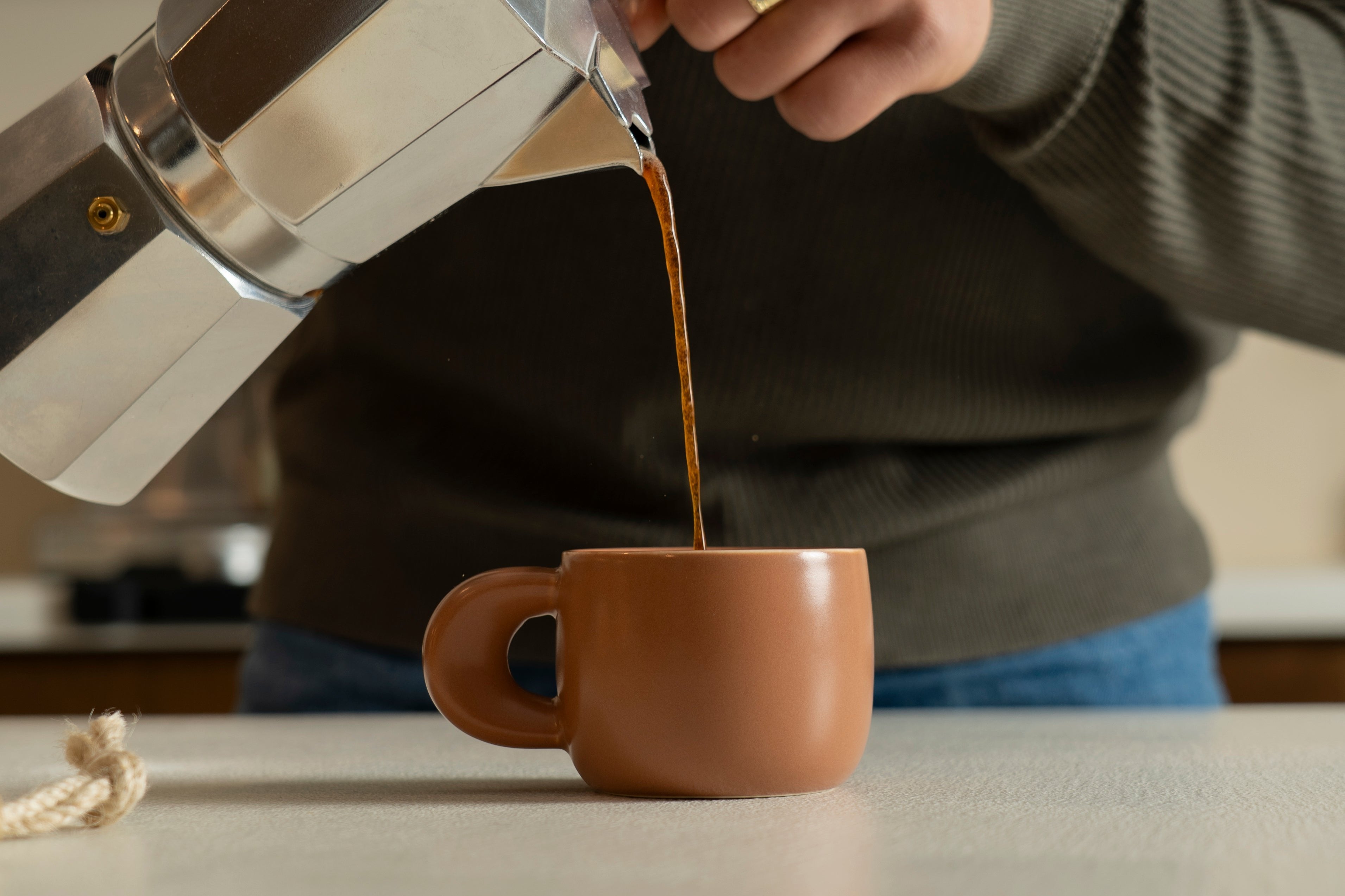 An image of pouring coffee into our ceramic cup Elegance in terracotta color